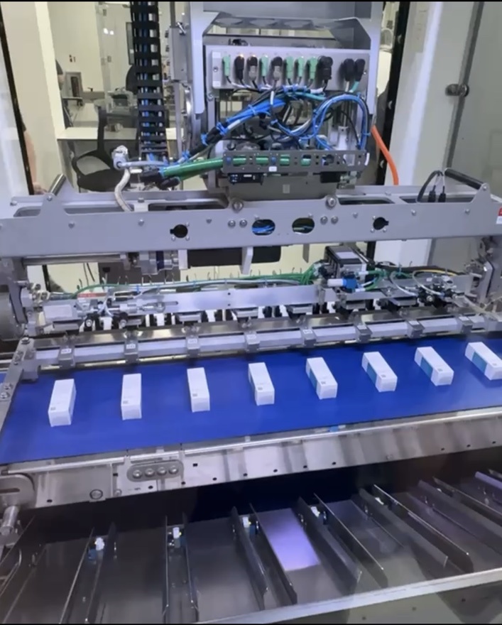Customer existing machine with closed cartons lying horizontally across the blue conveyor